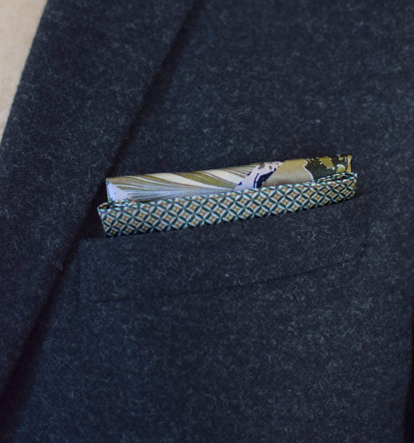This Marble Camo pocket square applies the flowing, layered quality of traditional hand-marbling to a palette of olive green, teal, black and ivory. Photographed folded into a neat rectangle showing the mid-section and order in a suit jacket.