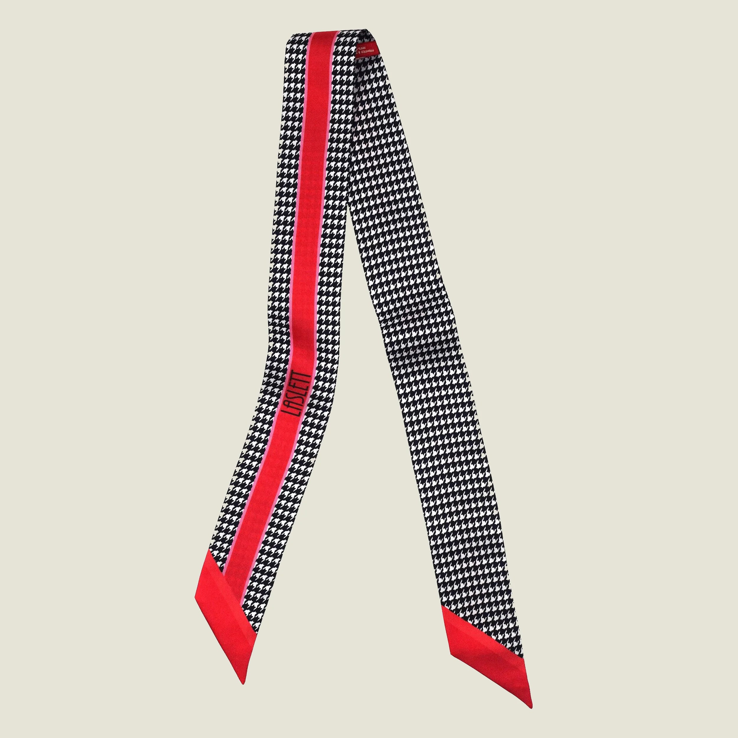100% silk Dogtooth Red Laslett Ribbon in black and red by Laslett England. Ribbon is shown in flat lay with the Laslett logo and contrasting pattern on each side.