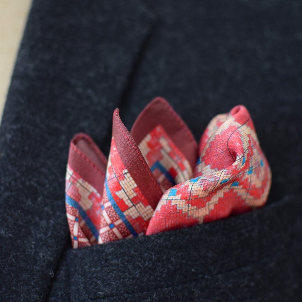 Laslett England Aztec Red pocket square in breast pocket of navy suit, red silk with geometric Aztec print