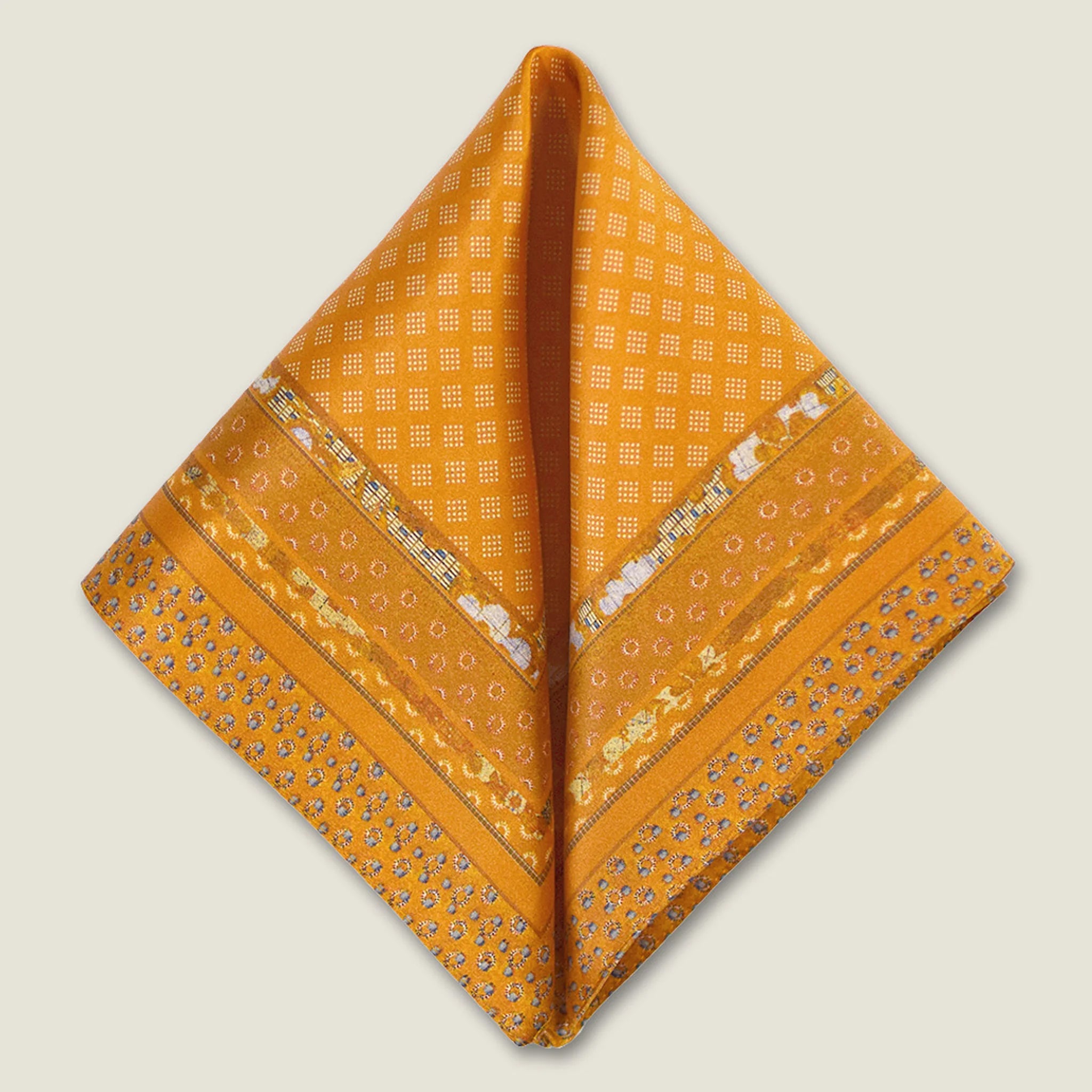 Batik Patchwork Gold pocket square in gold with an intricate patchwork of geometric patterns. Scarf is shown folded into two triangles against a neutral background.