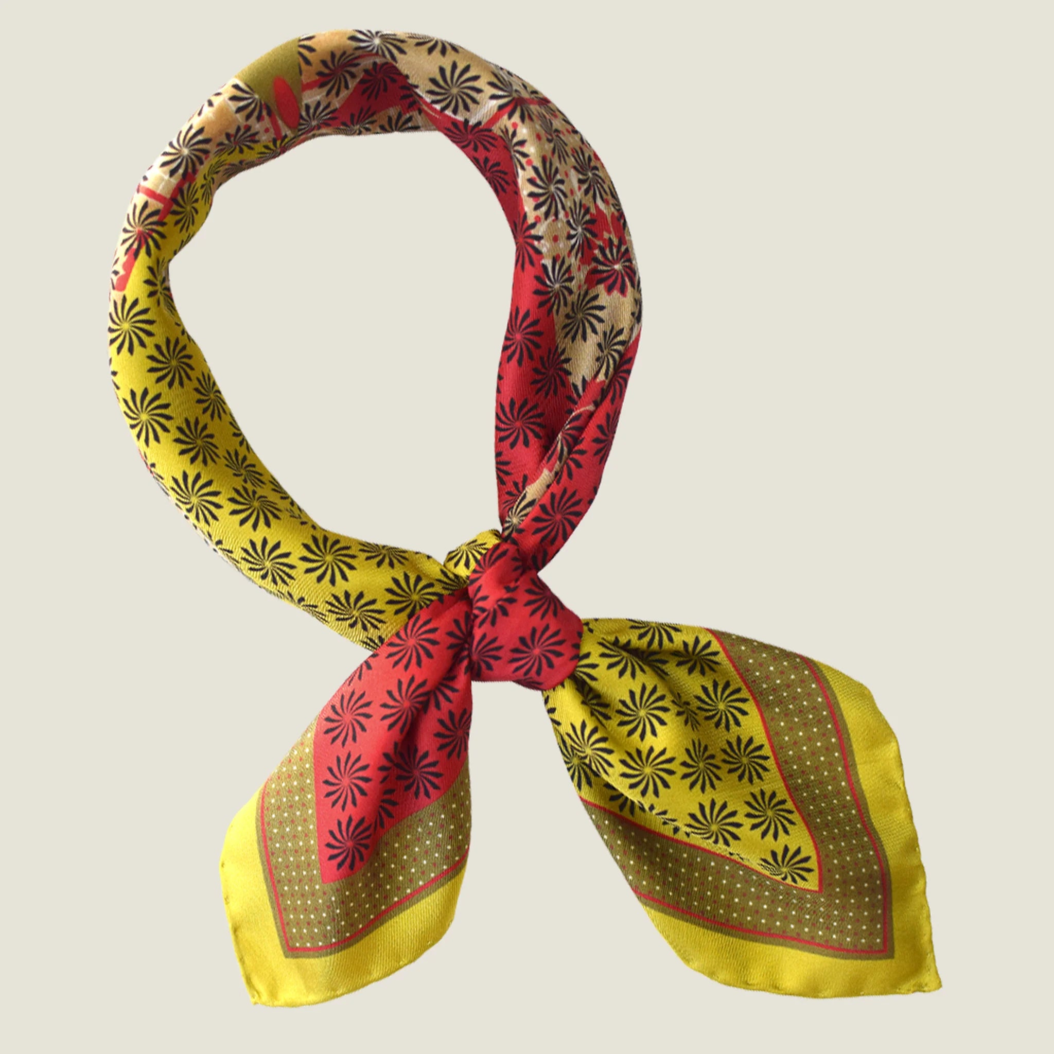 Laslett England Cadiz Silk Bandana knotted cowboy style at neck, showing camel and red sections of radiating multi-pattern print on silk twill.