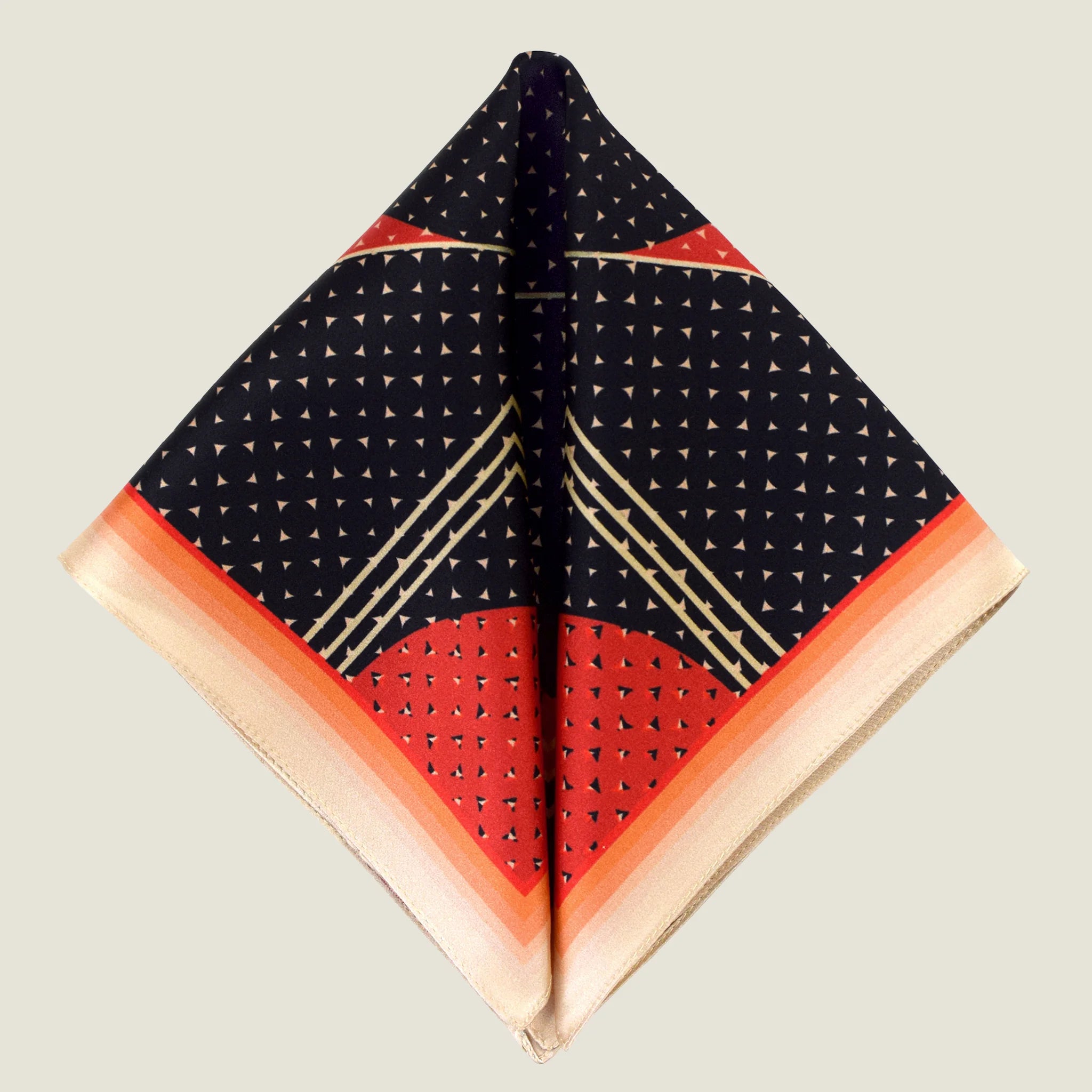 Laslett England Deco Noir pocket square corner detail, red and gold geometric border on black silk with triangle dot ground. Square shown folded into two triangles on a neutral background.
