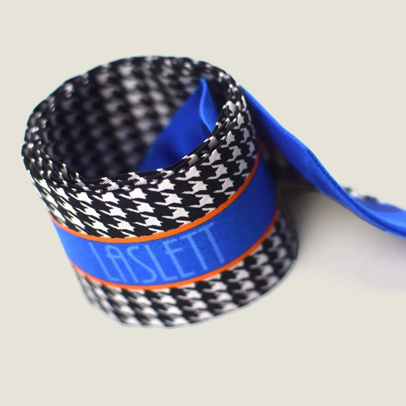 100% silk Dogtooth Blue Laslett Ribbon in black and blue by Laslett England. Ribbon is shown rolled up neatly to show the 'Laslett' signature.