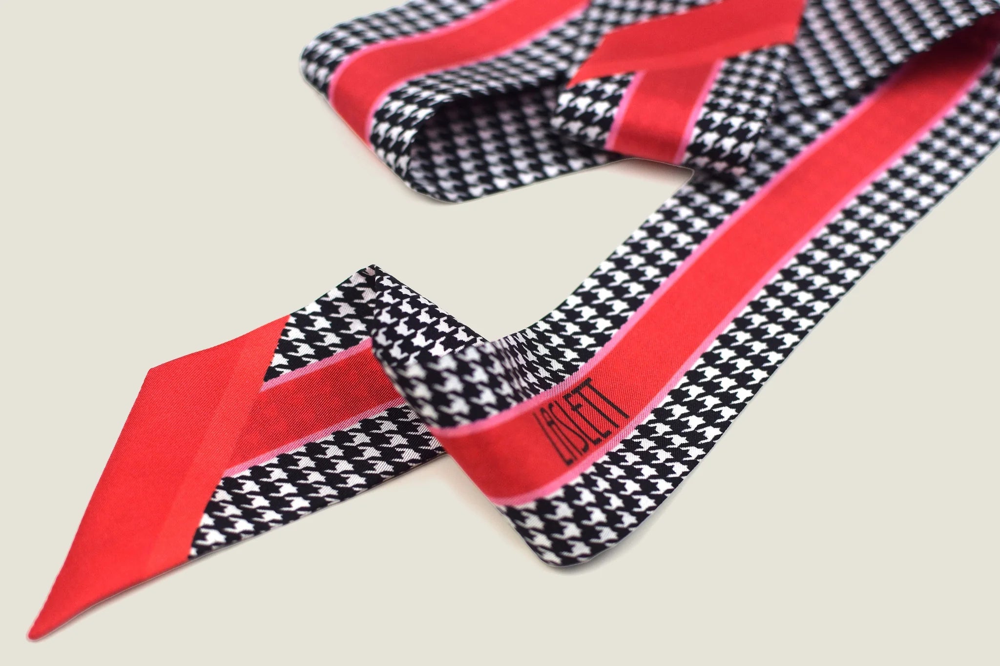100% silk Dogtooth Red Laslett Ribbon in black and red by Laslett England. Ribbon is shown loosely rumpled against a neutral background.