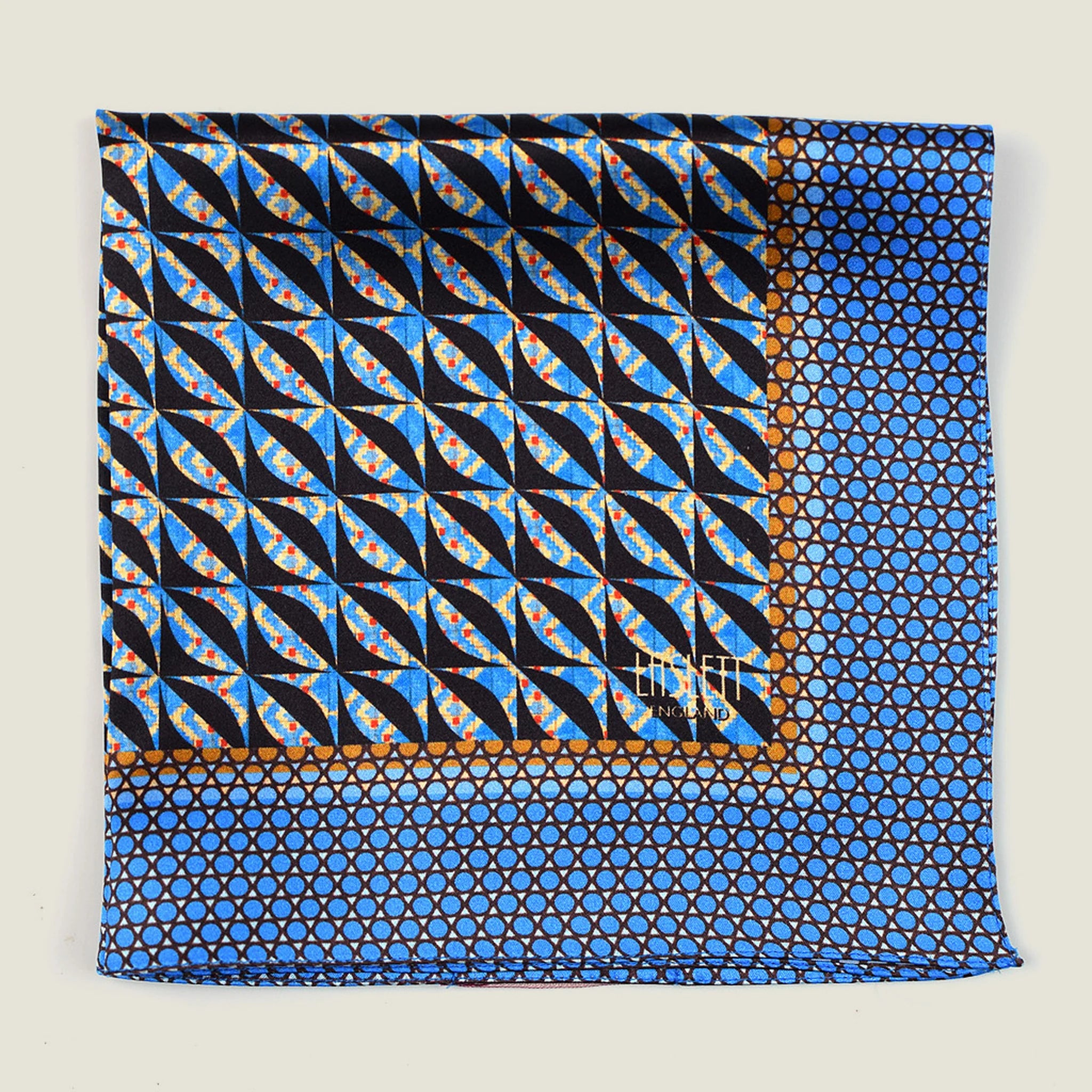 The 100% silk Havana Blue pocket square has a pale blue ground with a diamond repeat carrying small floral motifs in orange, red and cream, finished with a fine geometric border. Square is shown folded into four in flat lay on a neutral background.