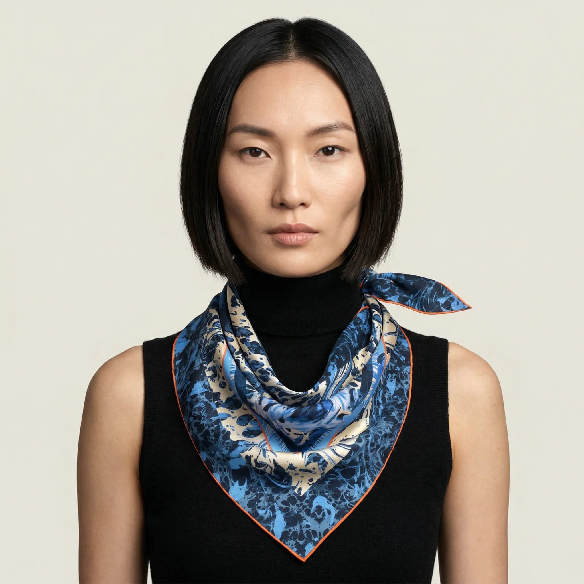 100% silk triangle Marble Rose Triangle Scarf in blue by Laslett England. Shown tied at the neck and worn by a model pictured against a neutral background.