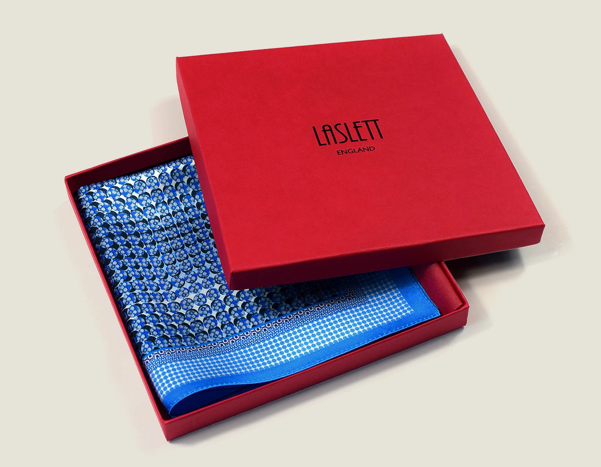 100% silk Matrix Blue pocket square has a distinctive geometric and repeating floral print in blue tones. Shown displayed in the signature red box.
