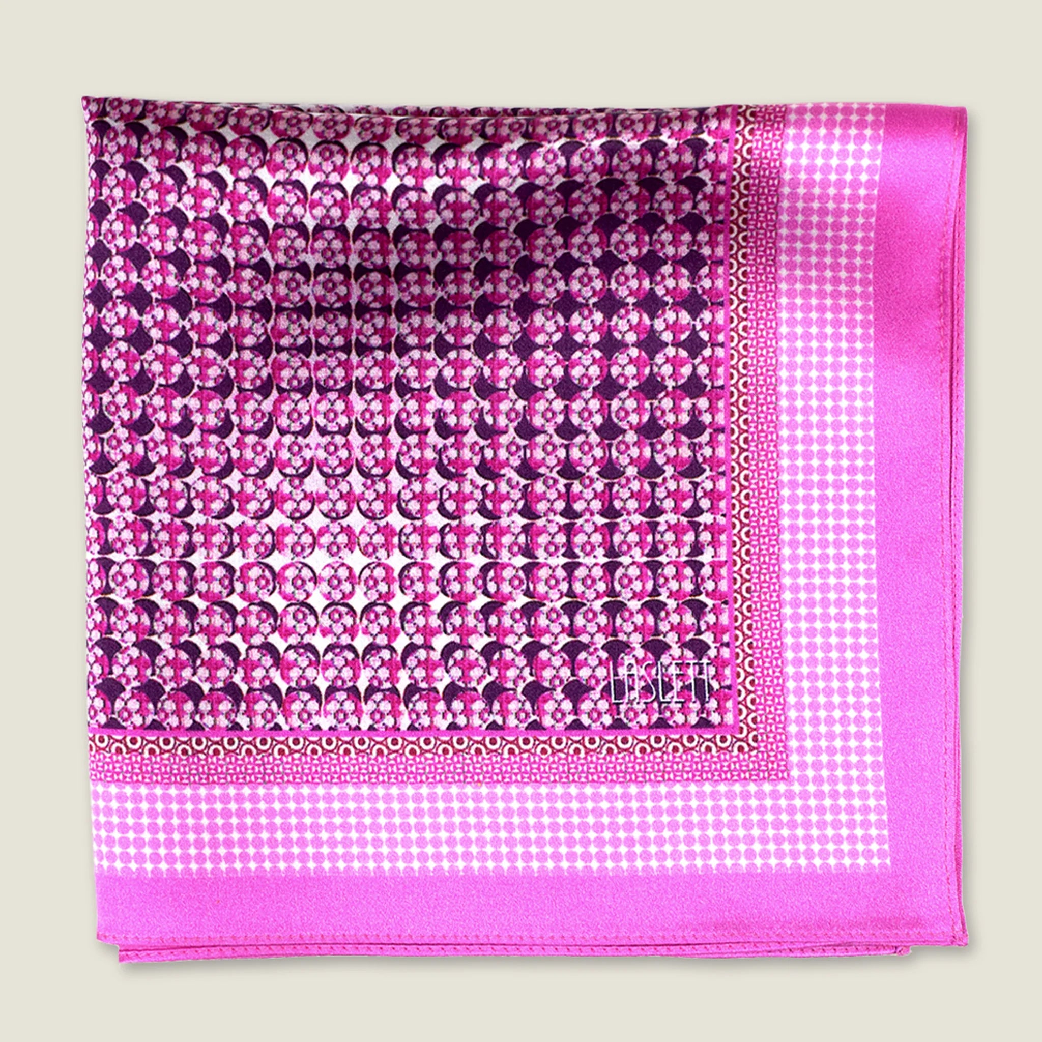 This Matrix Pink pocket square has a striking geometric design that reveals, on closer inspection, repeating graphic lines and patterns. In soft dusty pink with charcoal and white, square is shown folded into four against a neutral background.