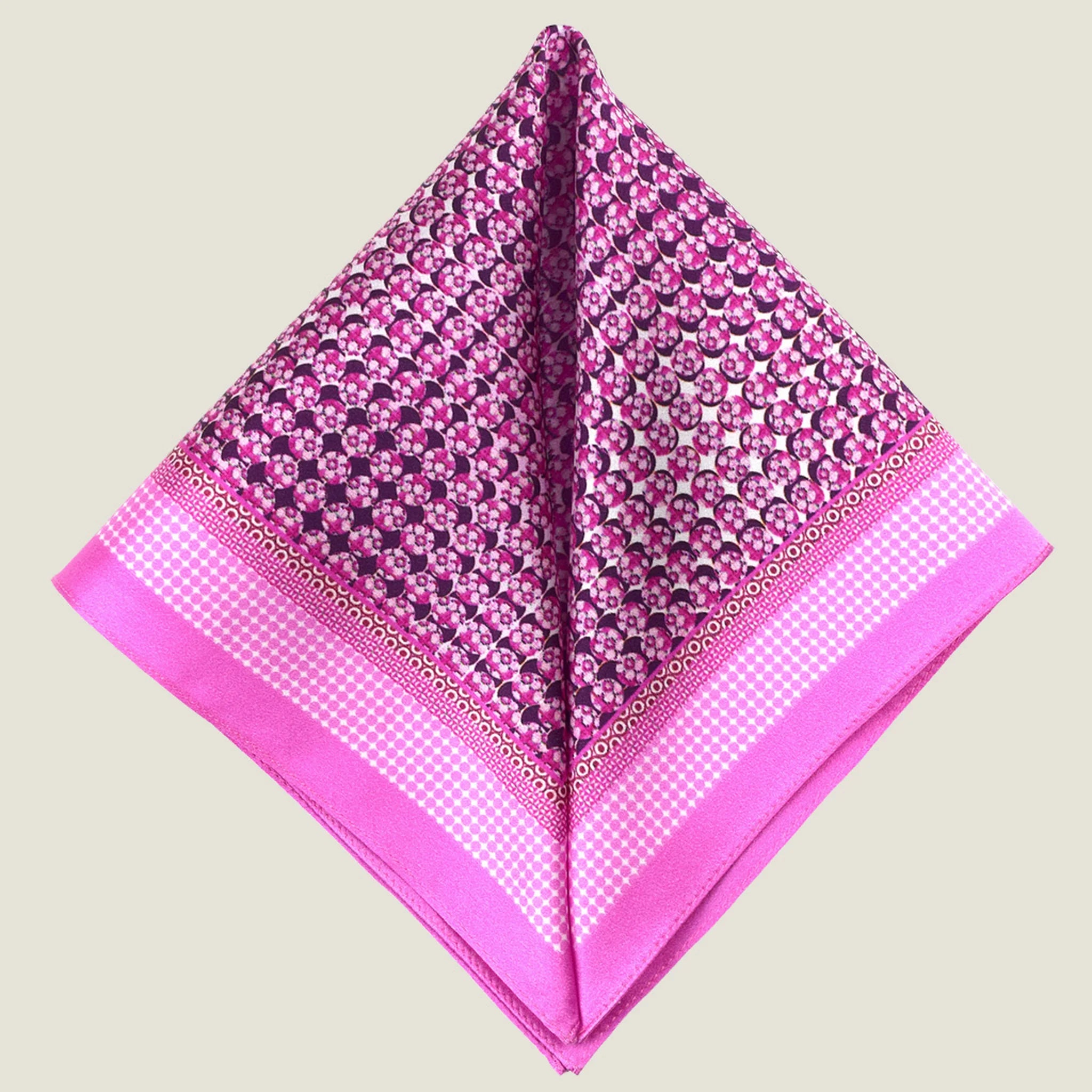 This Matrix Pink pocket square has a striking geometric design that reveals, on closer inspection, repeating graphic lines and patterns. In soft dusty pink with charcoal and white, square is shown folded into two triangles against a neutral background.