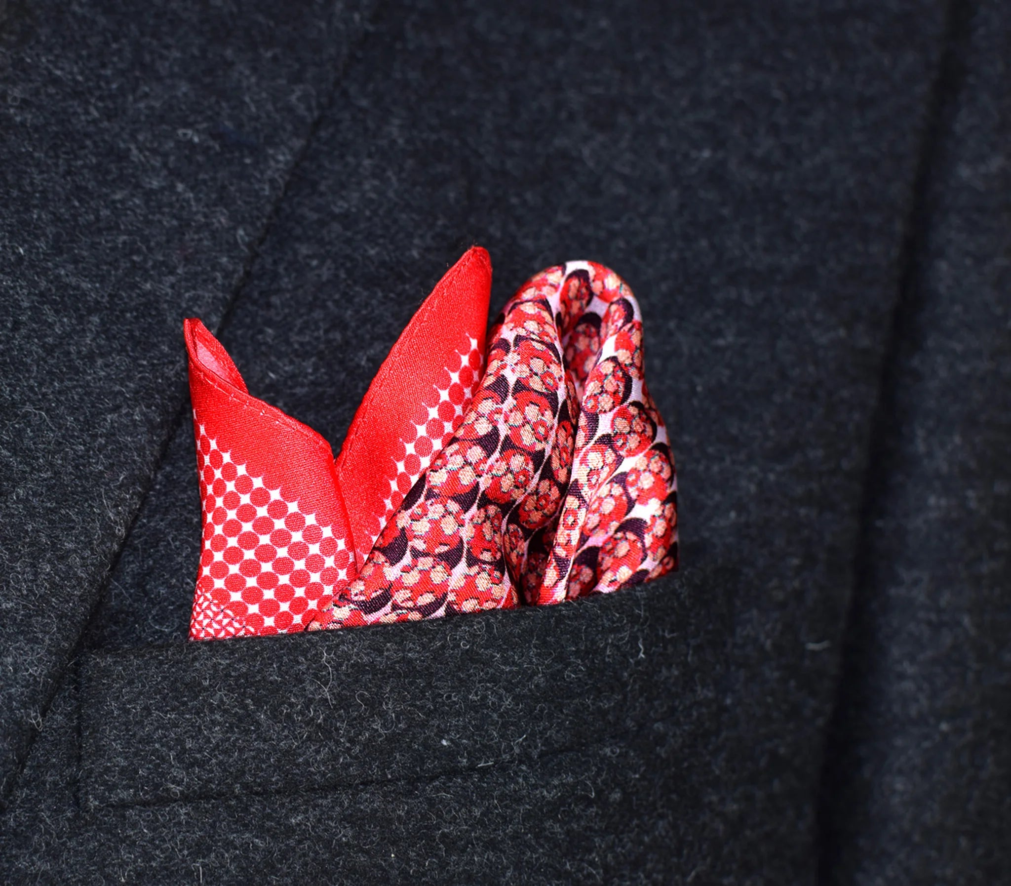 100% Matrix Red pocket square has a geometric design with a floral repeat that reveals itself on closer inspection. Square is shown arranged into a charcoal suit jacket.