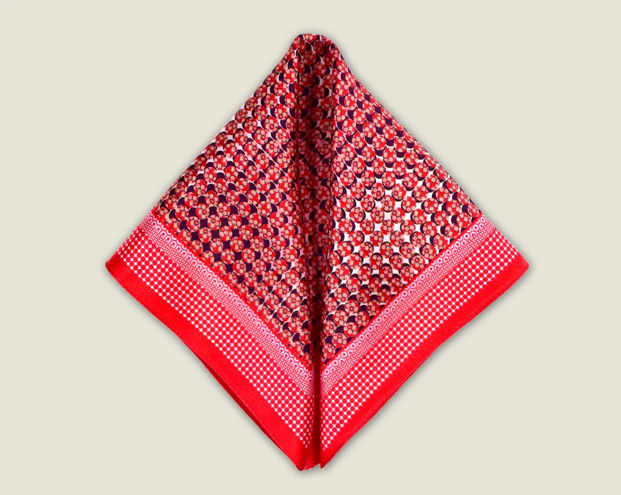 100% Matrix Red pocket square has a geometric design with a floral repeat that reveals itself on closer inspection. Square is shown folded into two triangles against a neutral background.