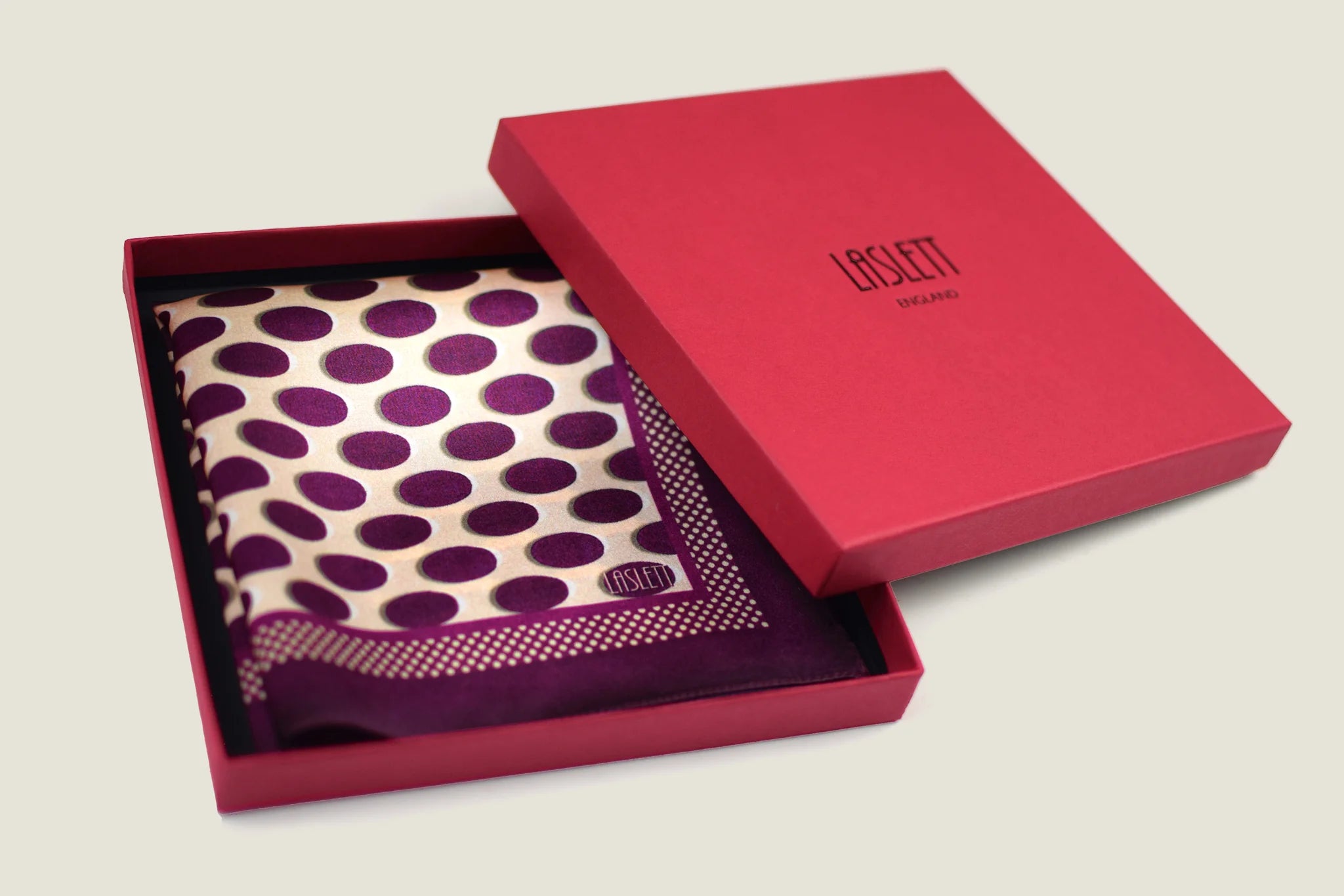 Oval Spot Burgundy pocket square from Laslett England is folded into four and displayed in the signature red box.