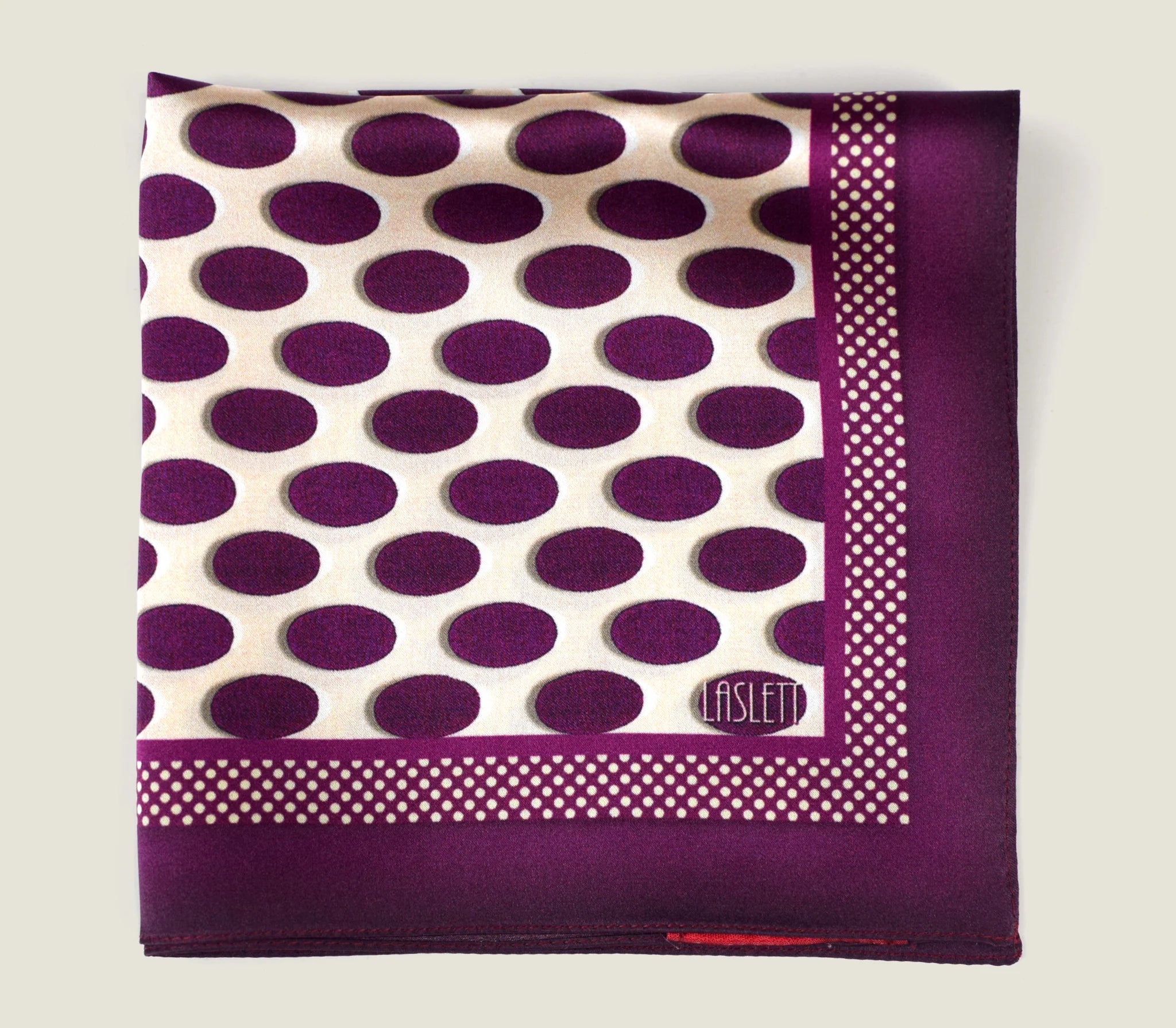 Oval Spot Burgundy pocket square shown folded into a quarter with the Laslett signature on display.