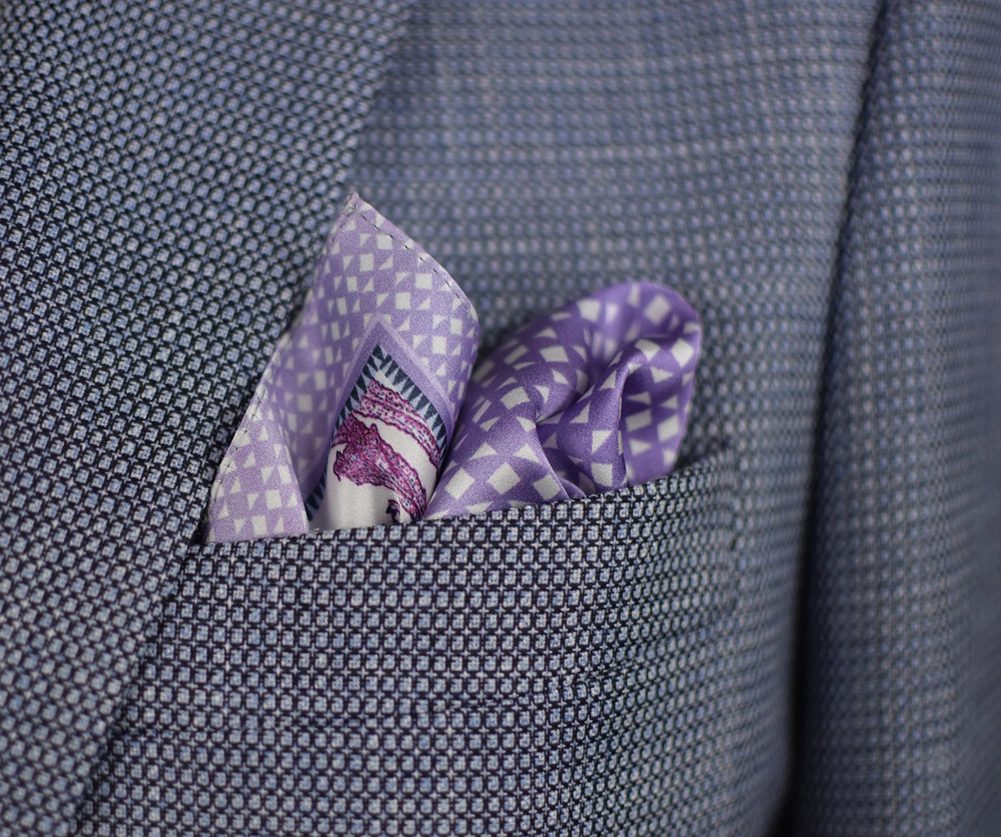 100% silk Panama Lilac pocket square takes its pattern from woven cane and straw, a geometric centre print in soft lilac and white with a botanical border of ferns in complementary tones. Photographed loosely arranged into a suit jacket.