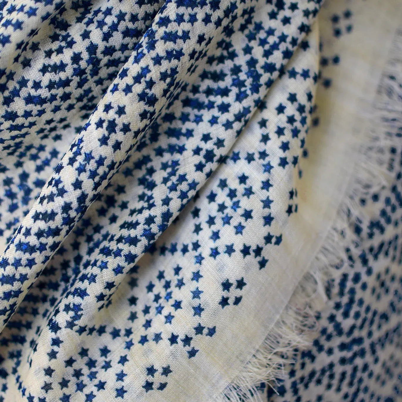 Laslett England Starry Cream Laslett Wrap flat lay, 120cm x 180cm superfine wool in cream ground with blue micro-star print and hand-fringed hem.