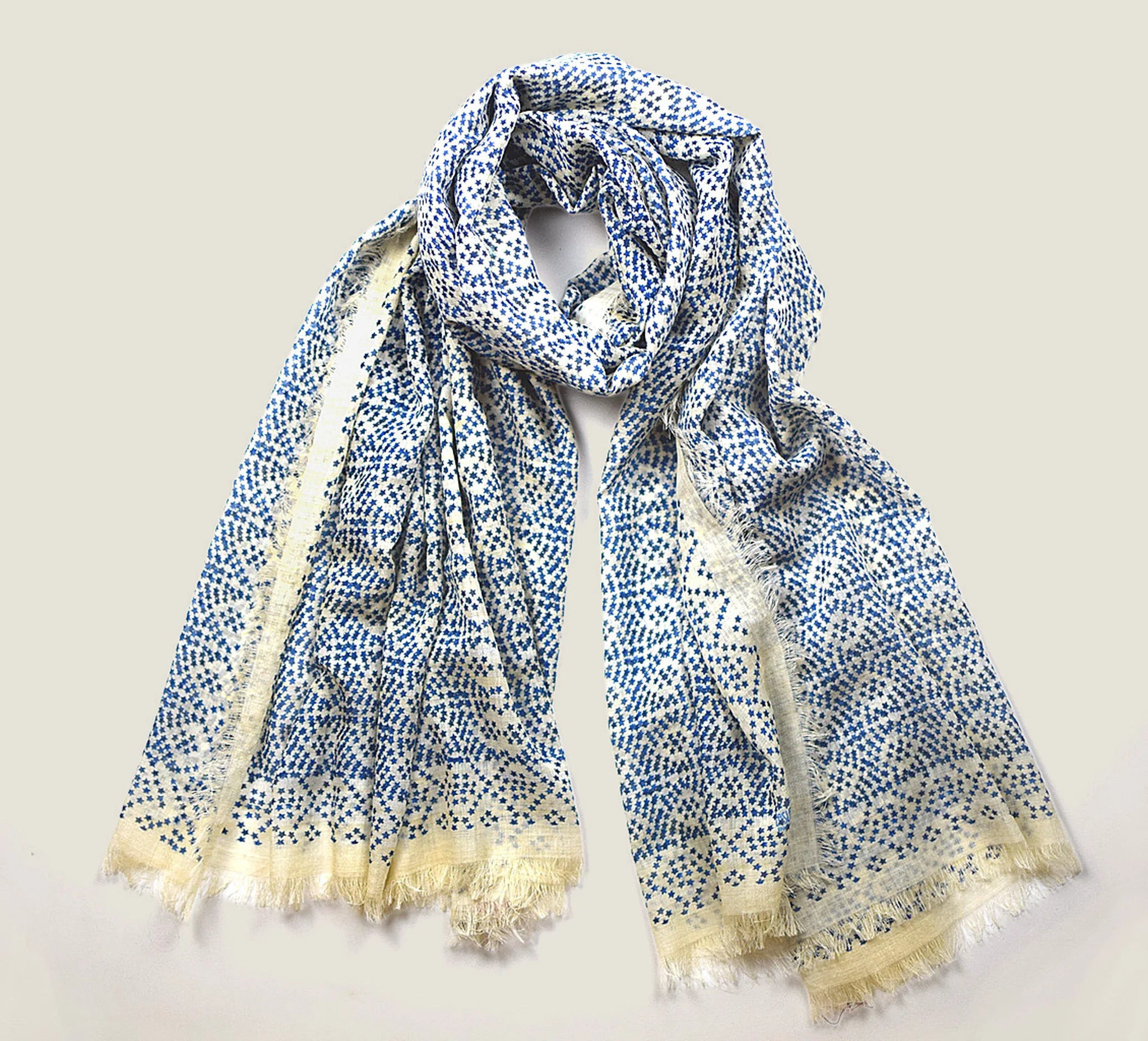 Laslett England Starry Cream Laslett Wrap folded and hanging, showing cream and blue micro-star print on superfine wool with hand-fringed hem