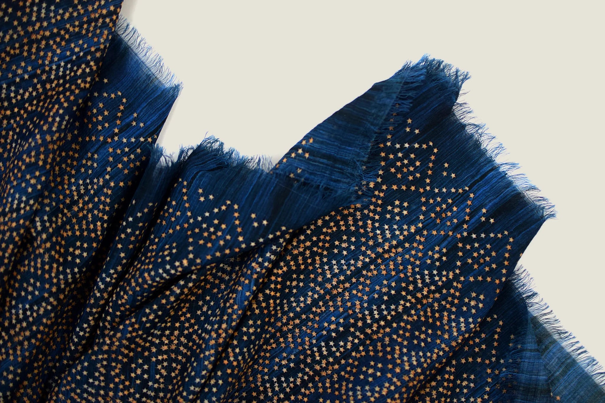 Laslett England Starry Indigo Laslett Wrap detail showing bronze and gold micro-star print on deep indigo superfine wool with hand-fringed hem