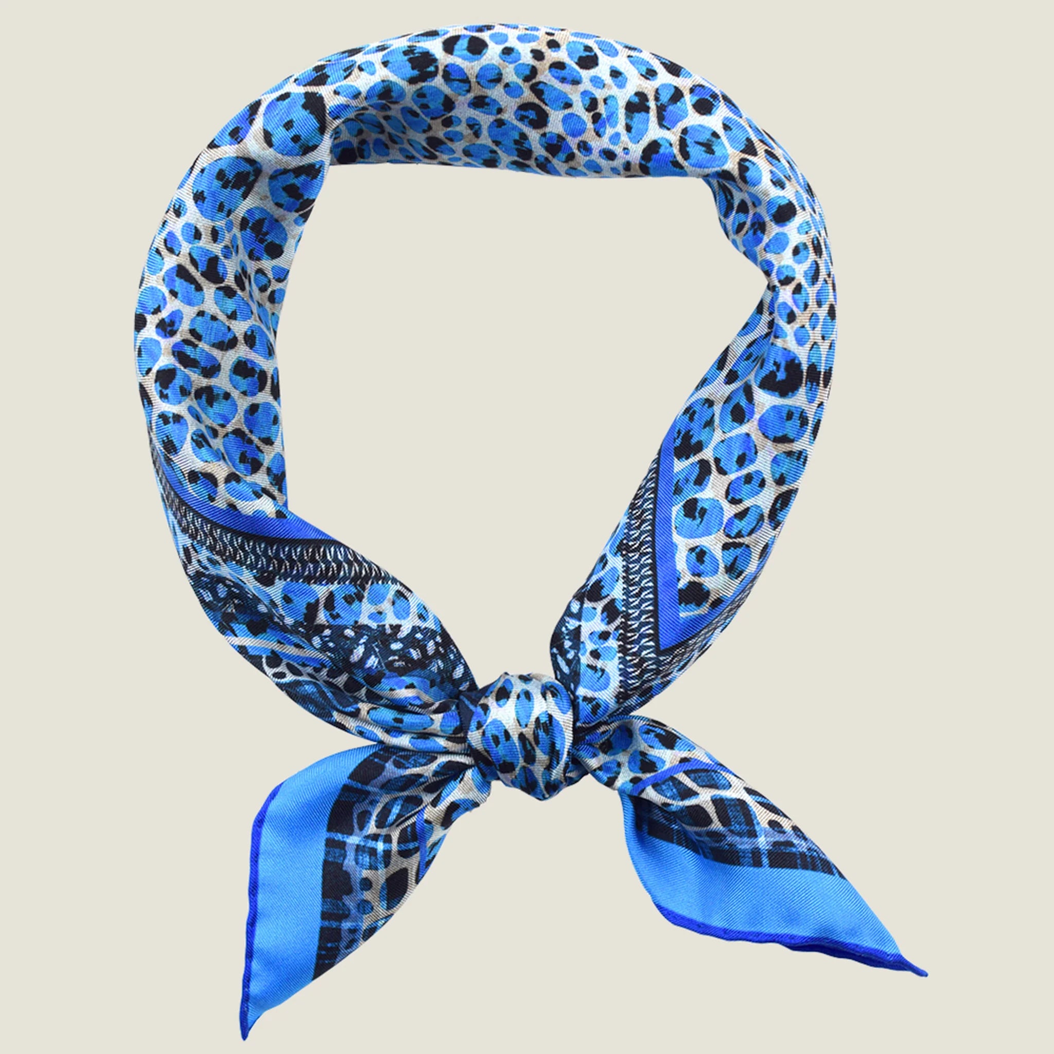 100% silk Tiger Moth Silk Bandana in blue with animal print by Laslett England. Shown knotted at the front against a neutral background.