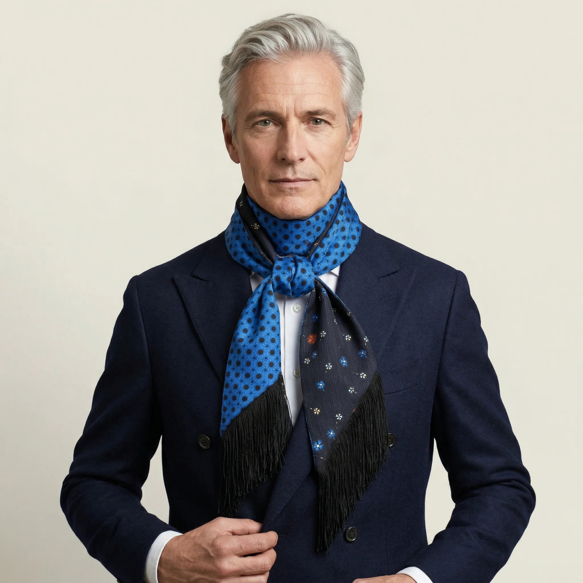 Laslett England Tuxedo Blue Fringed Silk Scarf worn at neck by male model in navy suit, cobalt blue side facing outward with black tassel fringe hanging down.