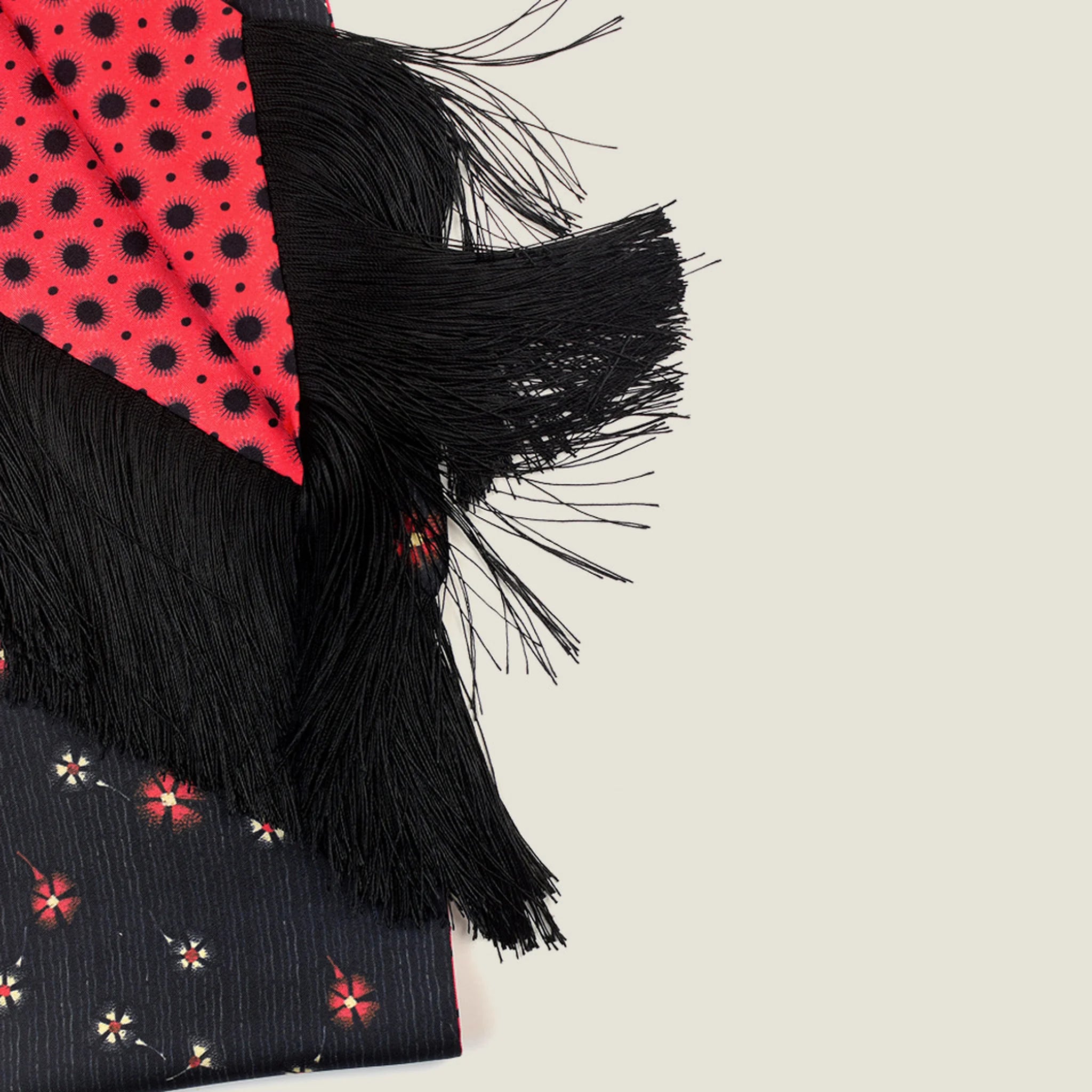 Laslett England Tuxedo Red Fringed Silk Scarf detail showing red ground with black geometric dot print alongside black with red floral pinstripe reverse and 10cm black tassel fringe.