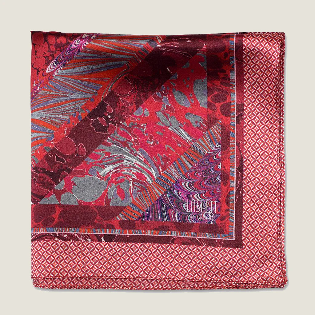 Laslett England Marble Red pocket square with red marbled interior and geometric edge pictured folded in four on flat lay.