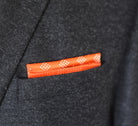 100% silk Batik Orange Pocket Square in orange by Laslett England shown folded into a flat square in a charcoal suit jacket pocket. 