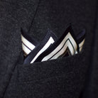 Laslett England Gambit Ivory pocket square in breast pocket of navy suit, black silk with white border and stripe detail.