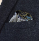 This Marble Camo pocket square applies the flowing, layered quality of traditional hand-marbling to a palette of olive green, teal, black and ivory. Photographed in a dark suit pocket. 