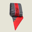 Red Dogtooth Laslett Ribbon pictured rolled up in product photograph with the Laslett logo on display. 