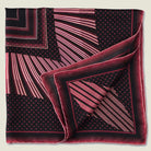 Houston Ruby Silk Bandana from Laslett England with a graphic radial stripe in ruby and rose pink pictured tied at the neck on a female model. Shown folded in four.