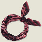 Houston Ruby Silk Bandana from Laslett England with a graphic radial stripe in ruby and rose pink pictured tied at the neck on a female model. Product shot tied at the back. 