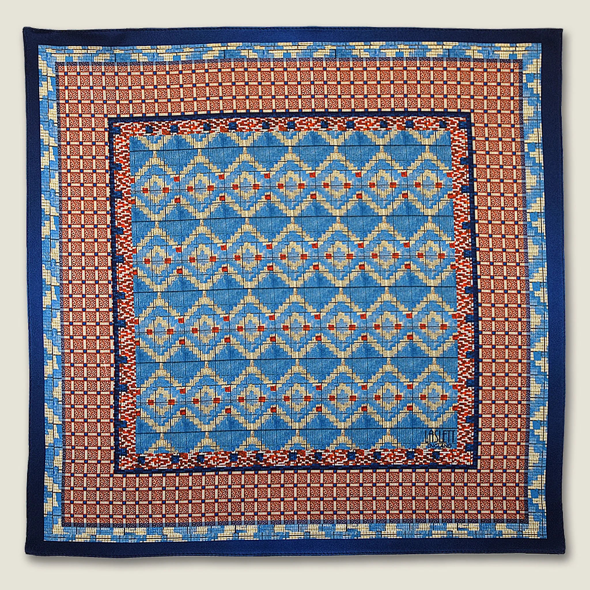 100% silk Aztec Blue Pocket Square in blue by Laslett England. Square is shown in a flat lay. 