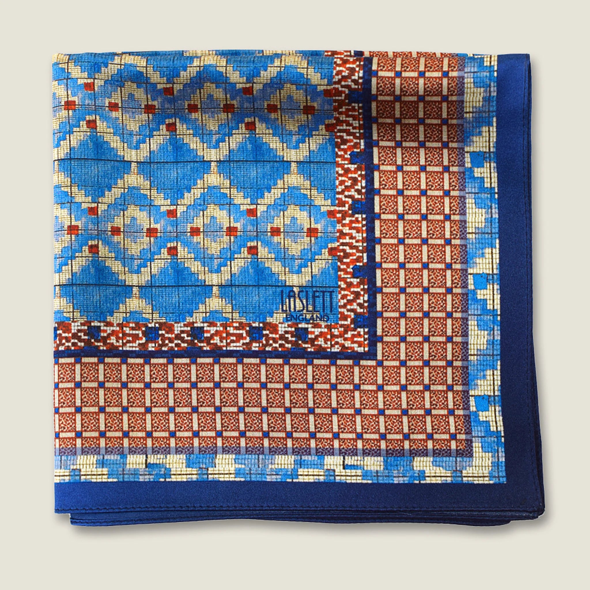 100% silk Aztec Blue Pocket Square in blue by Laslett England. The square is shown folded into 4 to show the Laslett England signature and the Aztec and geometric patterns. 