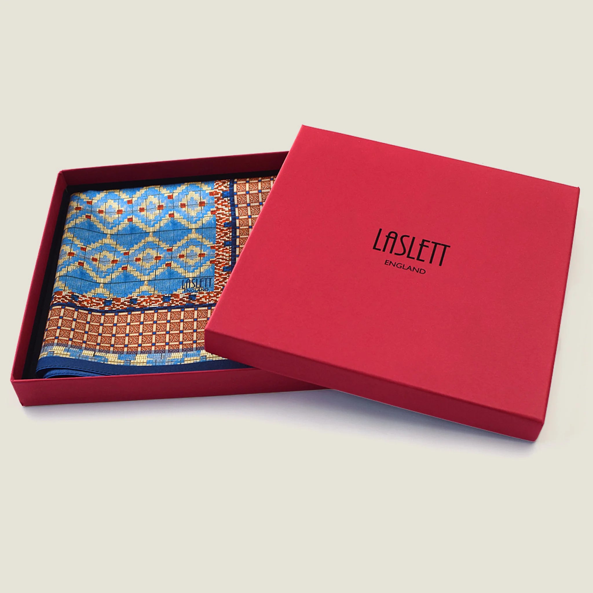 100% silk Aztec Blue Pocket Square in blue by Laslett England. Square is shown folded into the signature red box. 
