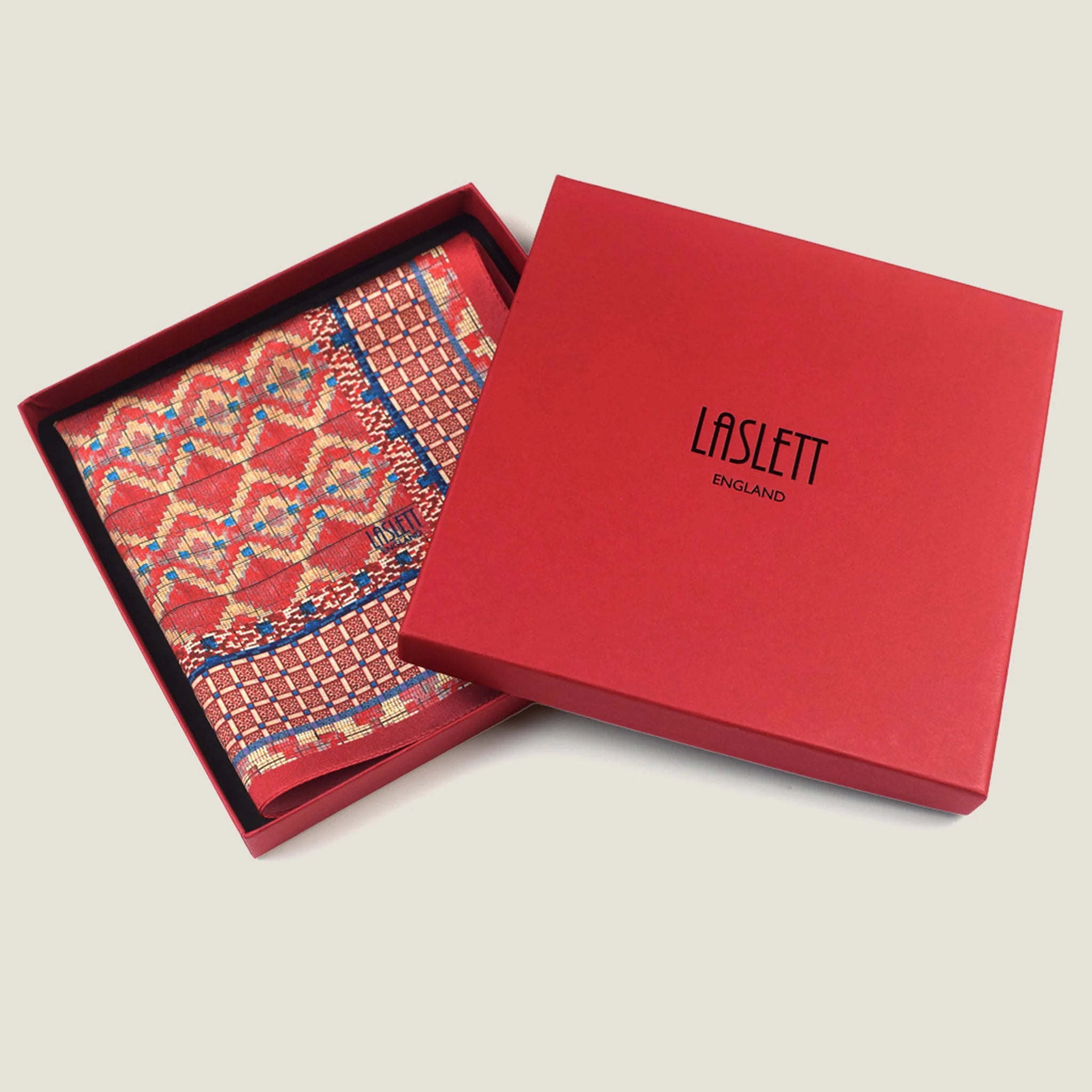 Laslett England Aztec Red pocket square flat lay, red ground with geometric Aztec repeat and navy border detail. Square shown folded in the signature red box. 