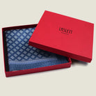 Batik Indigo pocket square has a deep ink blue ground with a geometric pattern in the batik tradition, finished with a gingham check border. Square is shown folded into the red signature Laslett England box. 