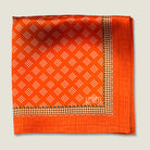 Batik orange pocket square shown folded in four with the Laslett logo showing in flat lay. 
