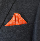 100% silk Batik Orange Pocket Square shown folded neatly into a charcoal suit pocket. 