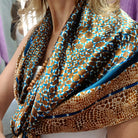 Laslett England silk scarf draped at neckline, close-up of teal and bronze animal print design.