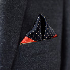 Laslett England Deco Noir pocket square worn in navy suit breast pocket, black ground with red Art Deco border.