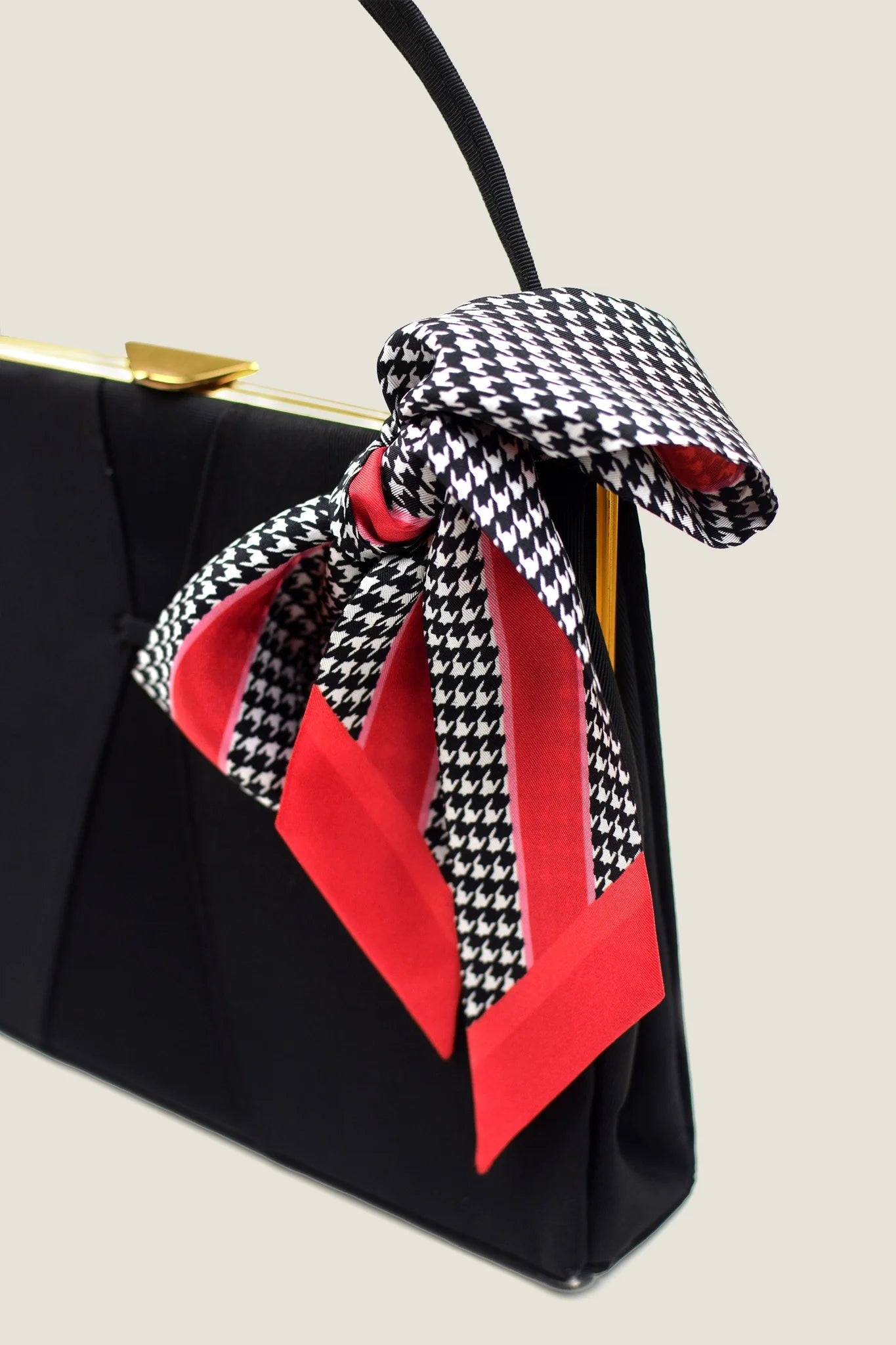 100% silk Dogtooth Red Laslett Ribbon in black and red by Laslett England. Ribbon is tied into a bow on a black handbag. 