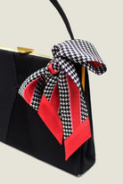 100% silk Dogtooth Red Laslett Ribbon in black and red by Laslett England. Ribbon is tied into a bow on a black handbag. 