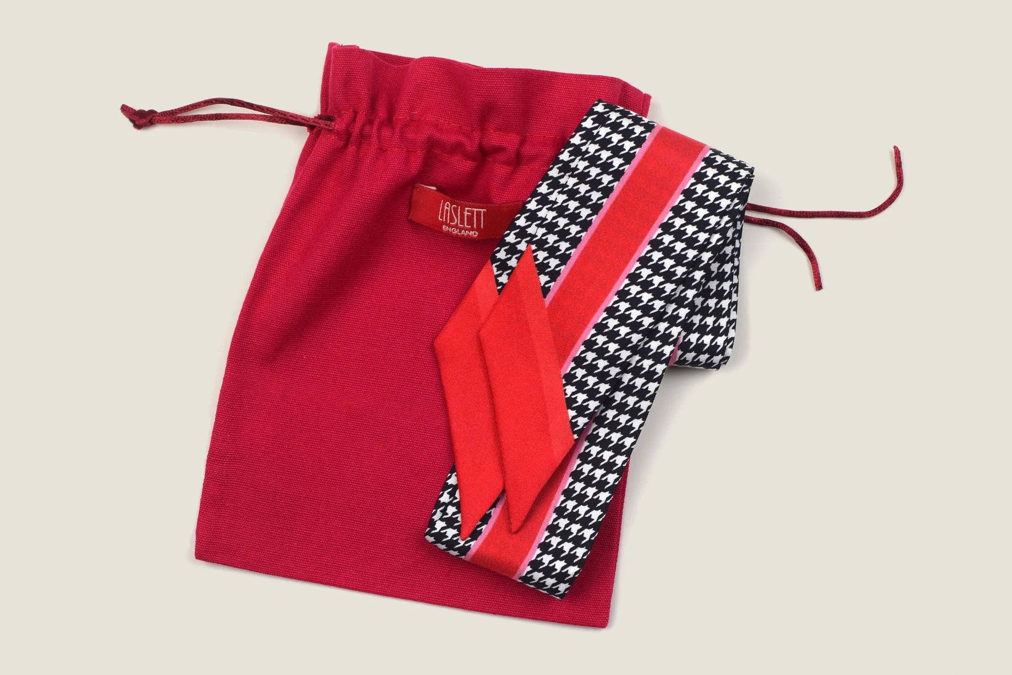 Laslett England Red Dogtooth Ribbon shown folded against the signature red pouch. 