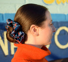 100% silk Chrome Blue Silk Scrunchie in blue by Laslett England photographed on a model in profile wearing a bun. 