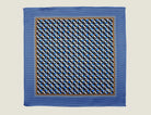 The 100% silk Havana Blue pocket square has a pale blue ground with a diamond repeat carrying small floral motifs in orange, red and cream, finished with a fine geometric border. Square is shown in flat lay on a neutral border. 