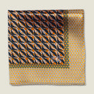 100% silk Havana Camel Pocket Square in gold and black with orange and green highlights by Laslett England. Scarf is folded in four against a neutral background with the Laslett England logo shown on the design. 