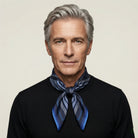 Laslett England Houston Midnight Silk Bandana worn knotted at neck by male model in black jacket, showing midnight blue radial stripe print.