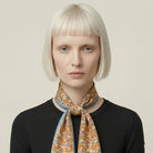 100% silk Laura Chiffon Stole in blue and yellow floral by Laslett England. Knotted at model's neck. 