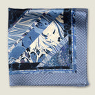 The Marble Blue pocket square print carries the flowing, layered quality of traditional hand-marbling in blue and cream tones with a geometric border. Photographed folded into four with the Laslett England logo on display. 