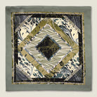 This Marble Camo pocket square applies the flowing, layered quality of traditional hand-marbling to a palette of olive green, teal, black and ivory. Photographed in flat lay. 